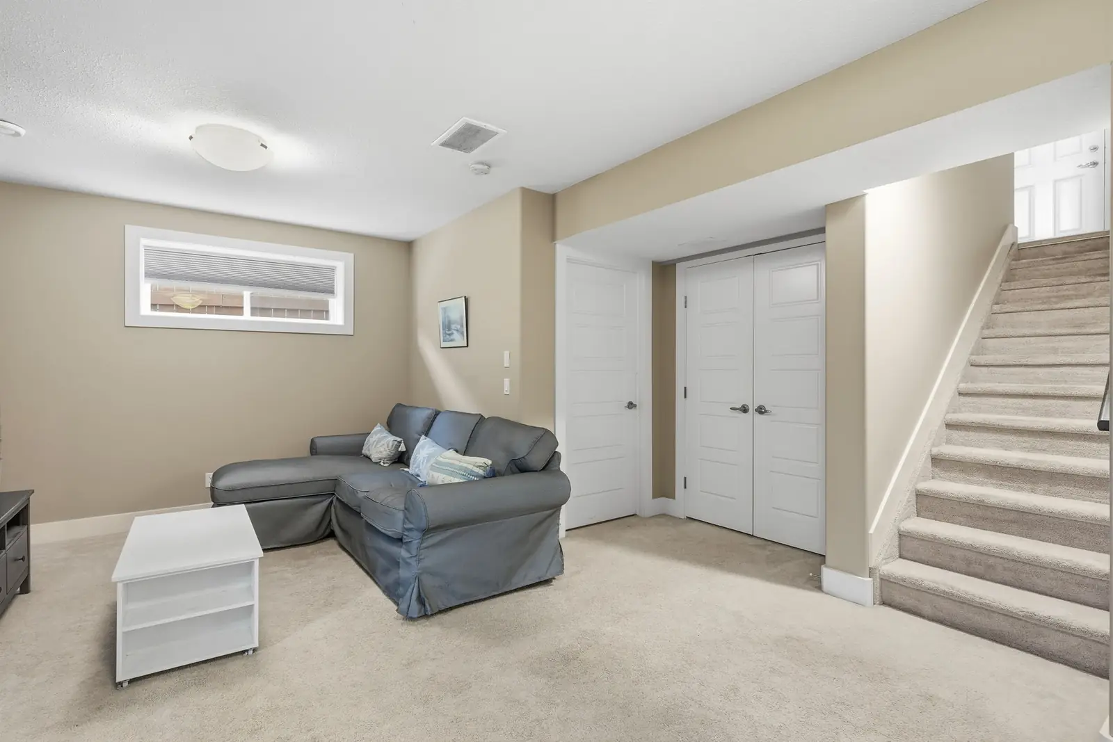 Finished basement family room with two large windows and the staircase